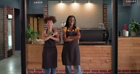 Smiling african american baristas standing behind rustic coffee counter with espresso