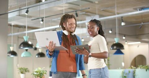 African american coworkers collaborating with laptop and tablet in modern open-plan office