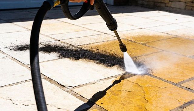 High-pressure patio cleaning on stone tiles removing heavy grime from outdoor terrace