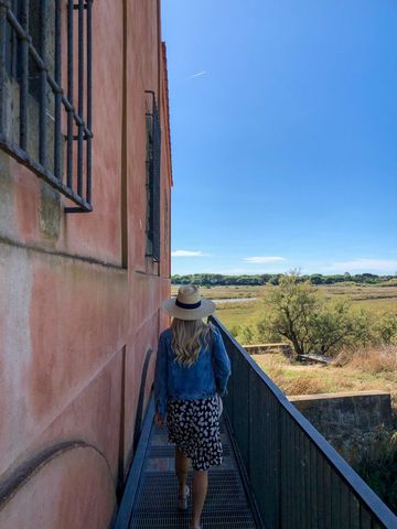 Woman in Sun Hat Strolling by Historic Rustic Building