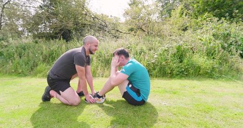 Two men performing sit-ups in park on sunny day