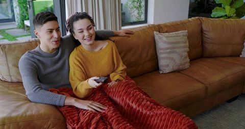 Couple Relaxing Together Under Blanket on Comfortable Leather Couch
