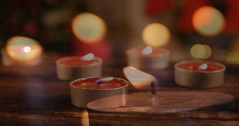 Flickering tealight candles on rustic wood table casting warm glow and bokeh ambience