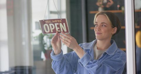 Female entrepreneur displaying open sign at hair salon entrance