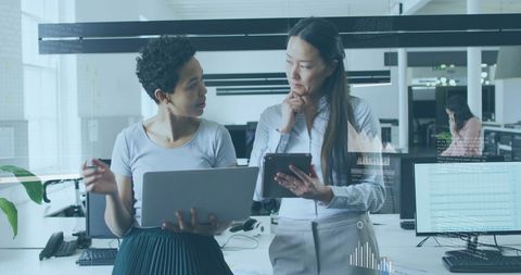 Two Businesswomen Collaborating Over Data and Technology in Modern Office