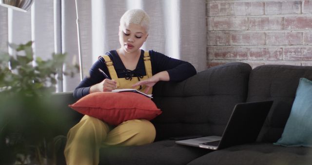 Young Woman Taking Notes on Sofa Near Laptop in Modern Living Space - Download Free Stock Images Pikwizard.com