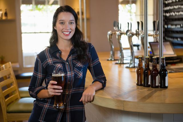Portrait of smiling young woman enjoying beer at restaurant