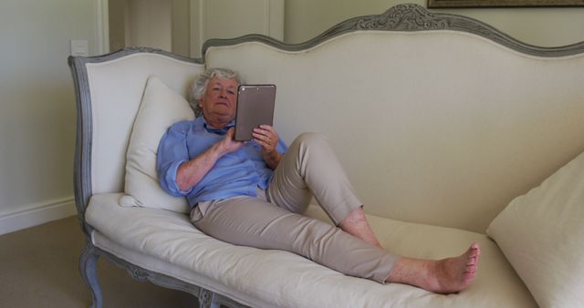 Caucasian senior woman using digital tablet while sitting on the couch at home - Download Free Stock Photos Pikwizard.com
