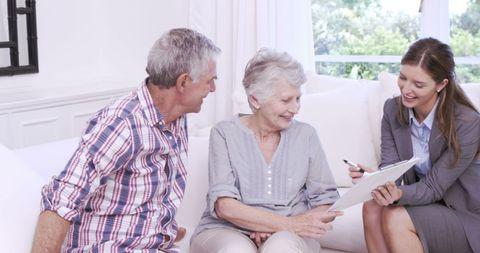 Businesswoman Presents Contract to Senior Couple on Sofa - Download Free Stock Images Pikwizard.com