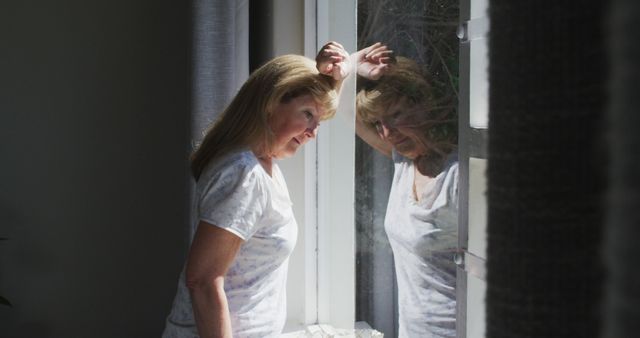 Pensive Mature Woman Looking Through Window Reflecting with Natural Light - Download Free Stock Images Pikwizard.com