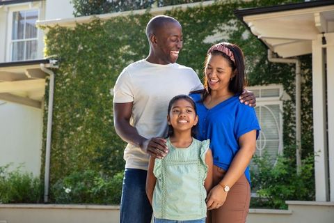 Happy family standing on their suburban home's front porch steps