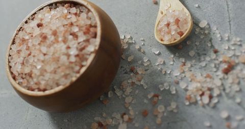 Himalayan Pink Salt in Wooden Bowl and Spoon on Stone Surface