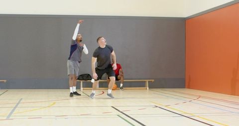 Indoor basketball players pointing and reacting during pickup game on hardwood court
