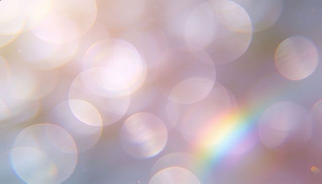 Pastel bokeh orbs creating dreamy prismatic glow with soft rainbow flare and refraction