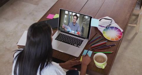 Female working remotely at home, writing sticky note during laptop call with color wheel