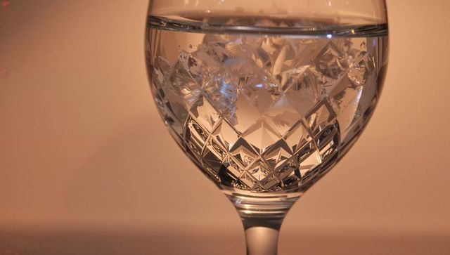 Cut crystal goblet reflecting warm amber light with faceted pattern and water line