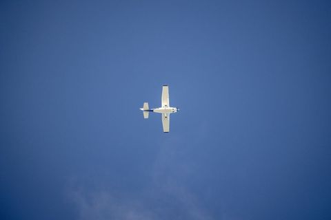 White Light Aircraft Soaring in Clear Blue Sky
