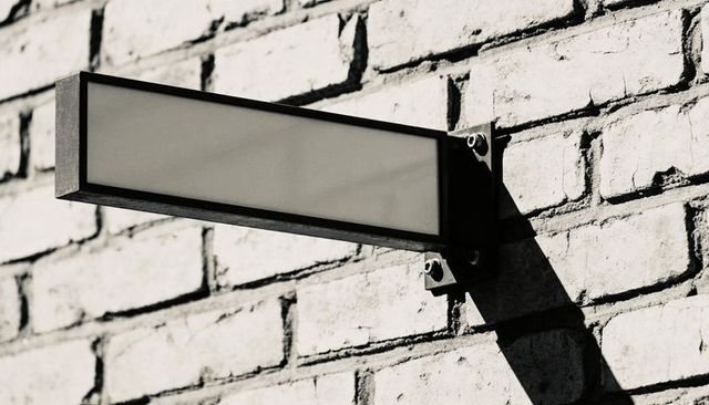 Blank Rectangular Metal Sign Casting Long Shadow on Painted Brick Wall Urban Mockup