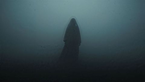Hooded figure shrouded in fog, symbolizing mystery and solitude