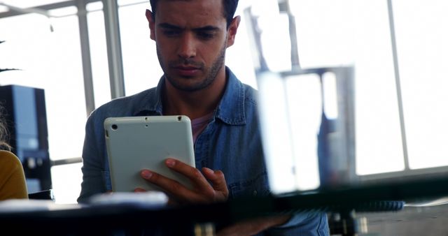 Young Man Concentrating on Tablet in Office Environment - Download Free Stock Images Pikwizard.com