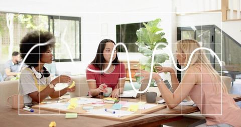 Diverse women collaborating over sticky notes and laptop during creative brainstorming session