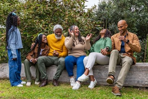 Multigenerational african american family laughing together on wooden bench outdoors