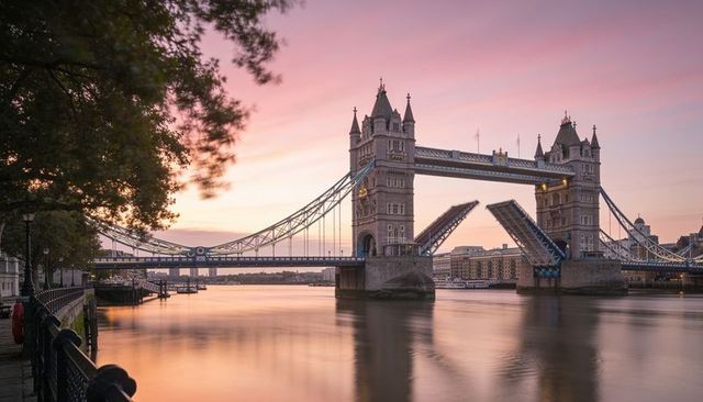 Tower bridge at sunset with raised bascule leaves over river thames london promenade