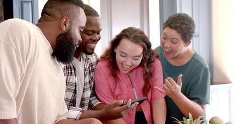 Diverse Friends Laughing Together While Looking at Smartphone