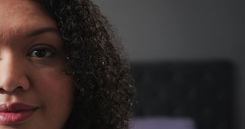 Closeup portrait mid-adult woman with curly hair and lipstick against tufted headboard