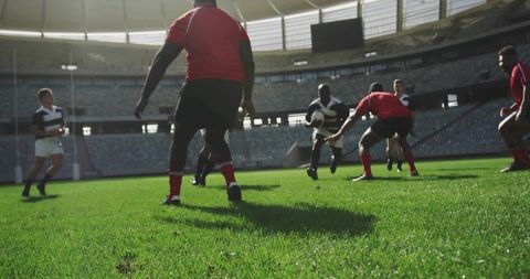 Rugby Players Tackling and Sprinting on Stadium Grass Pitch During Competitive Match