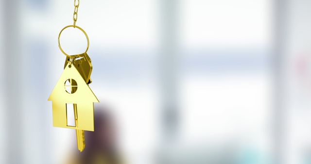 Image of gold house key fob and key dangling over out of focus interiors with copy space. Home ownership concept digitally generated image.