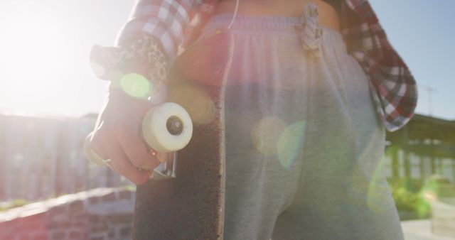 Midsection of caucasian woman holding skateboard on sunny day - Download Free Stock Photos Pikwizard.com