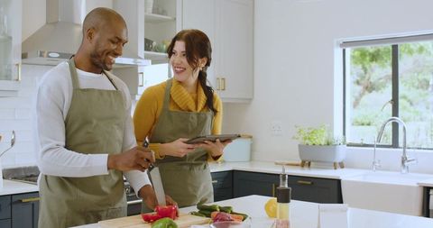 Smiling Couple Cooking & Using Tablet for Recipe Instructions