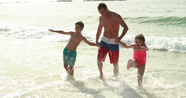 Father engaging with children in playful activity on sunny beach by ocean waves. Ideal for promoting family vacations, summer holidays, outdoor recreation, and content centered around parent-child bonding.