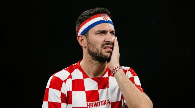 Anxious croatian football fan touching cheek wearing hrvatska jersey and headband