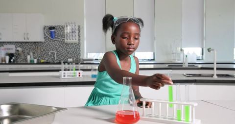 African schoolgirl conducting colorful chemistry experiment with test tubes and flask