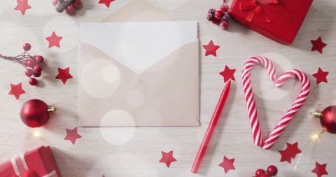 Sending holiday wishes with candy cane heart, cream envelope, red pencil and gifts