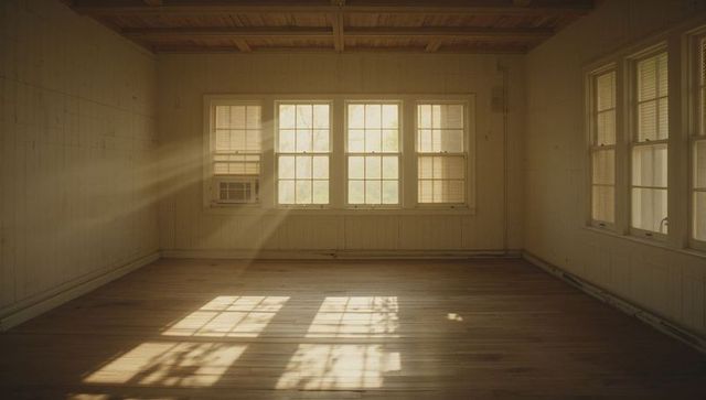 Sunlit empty sunroom bathing in late-afternoon rays with hardwood floor and timber beams