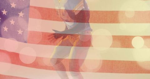Jumping black man in t-shirt and jeans with american flag overlay and colorful bokeh