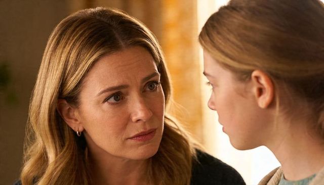 Concerned mother talking to daughter in warm light, intimate closeup emotionally charged