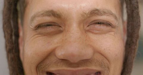 Warm close-up smiling man with freckles and dreadlocks conveying natural texture and joy