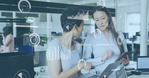 Women collaborating in office with data analytics overlay
