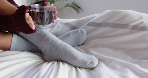 Cozy comfort with grey socks and glass mug on bed