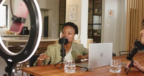 African American Podcaster Recording Lively Conversation with Co-Host in Cozy Home Studio