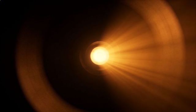 Radiating amber sunburst with halo rings and radial light beams over dark abstract