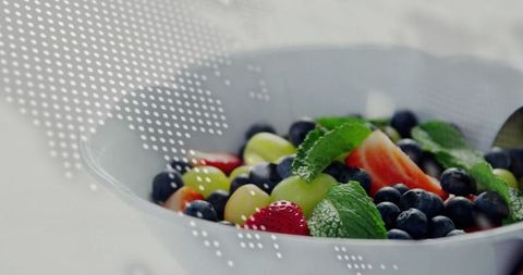Vibrant mix of fresh fruits in white bowl with artistic overlay