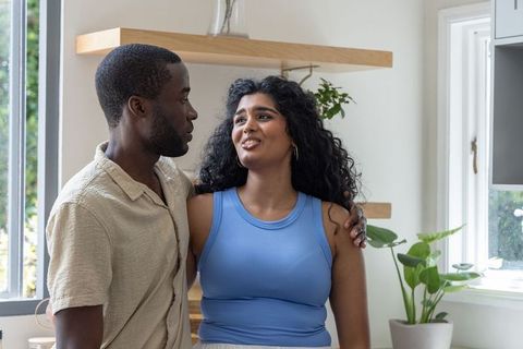Indian woman and african american man sharing tender moment in bright kitchen with greenery