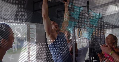 Man doing pull-up while group cheering during intense crossfit workout in urban gym