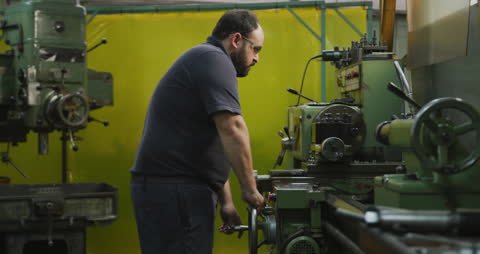 Factory Worker Operating Machinery in Industrial Workshop