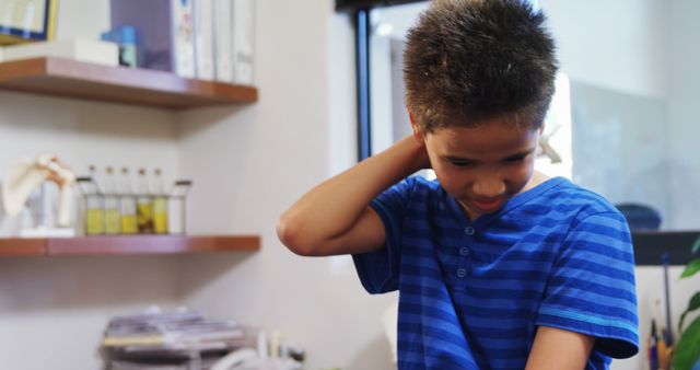 Young boy appears to be scratching his neck while in a doctor's office, next to shelves and medical files. Ideal for depicting children's healthcare, medical appointments, or clinic environments.